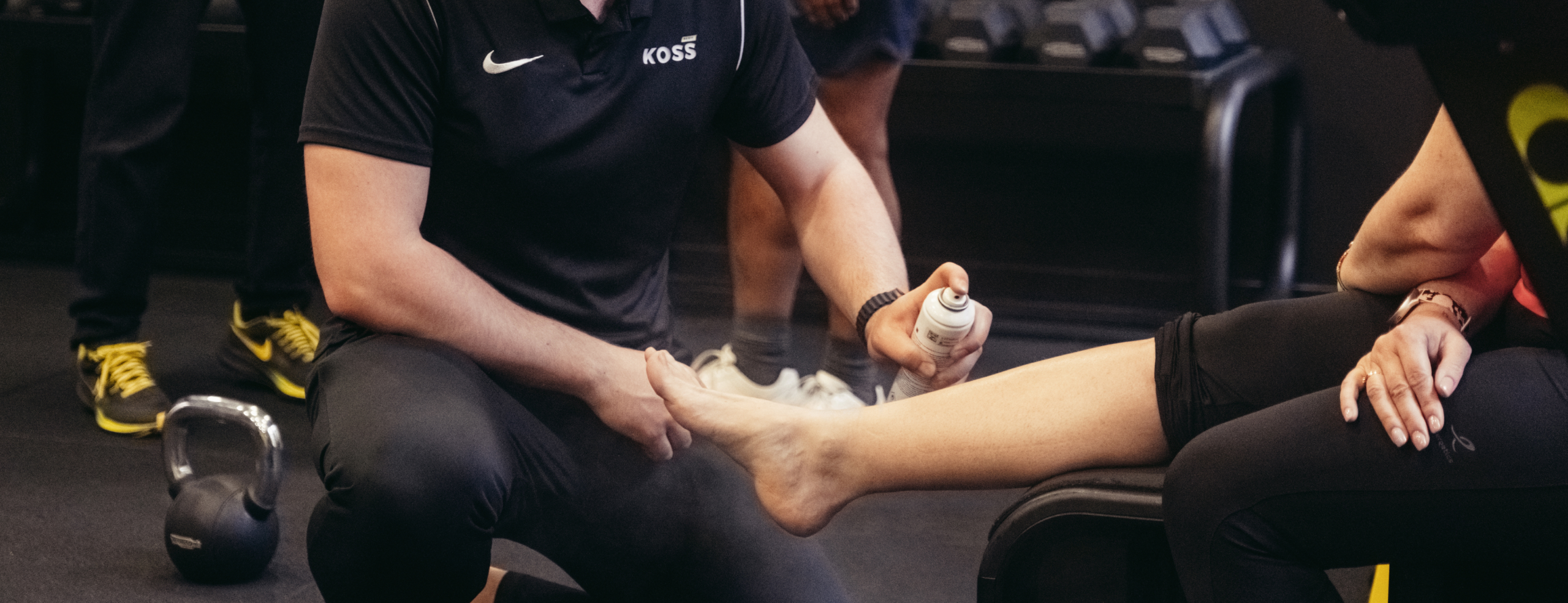 Kinésithérapeute appliquant un spray de récupération sur la jambe d’un patient - Role de kiné | Koss Sport Paris