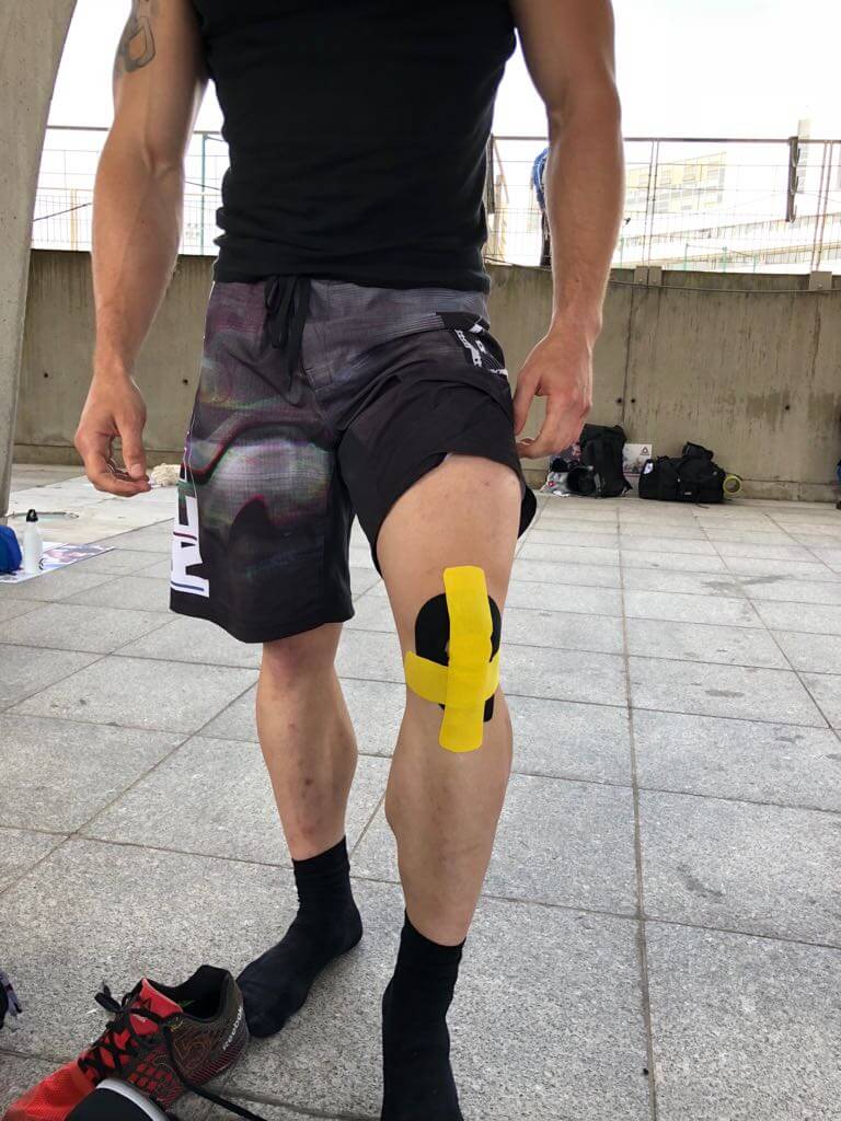 Homme debout portant une K-tape sur le genou avant le sport