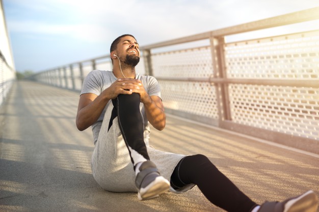 sportif blessé avec douleur au genou lors de la pratique de son sport